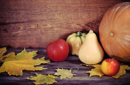 Autumn leaves, apples and pumpkins on the wooden backgroundの写真素材
