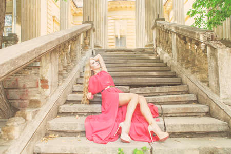 Beautiful blond woman in long red dress outdoorsの写真素材