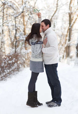 Happy young couple under mistletoe having fun in the winter parkの写真素材