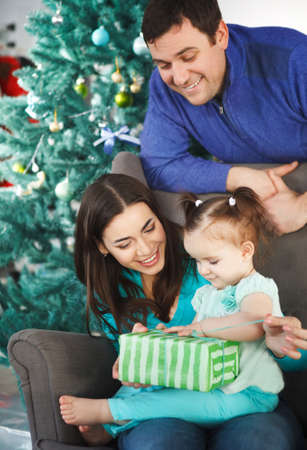 Happy family with Christmas present near the Christmas treeの写真素材