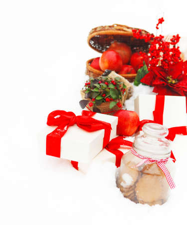 Christmas still life with a Christmas decorations, cookies, apples and presents nestling in fresh snowの写真素材