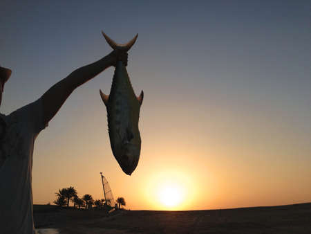 Young man with big Queen fish that was catched by him on a oceanの写真素材