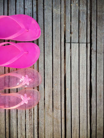 Brightly colored pink flip-flops of a mother and daughter on wood. Family vacationの写真素材