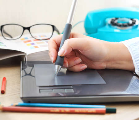Graphic designer working in office with tablet pen. Selective focus on digital penの写真素材