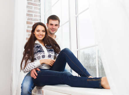Couple in love at home relaxing on the windowの写真素材