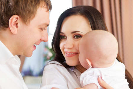 Happy smiling family with little baby girl indoor