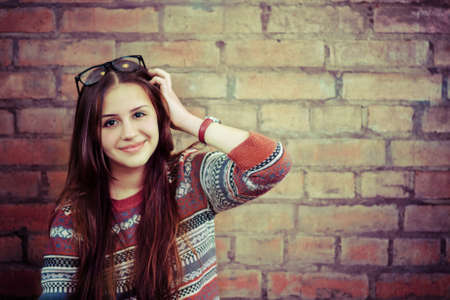 Close up portrait of a beautiful cute teen girl smilling near the brick wall