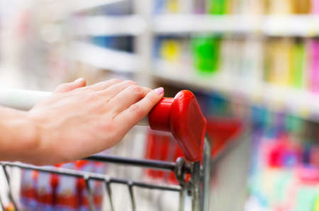 Closeup of the hand of female shopper on the trolley at supermarketの写真素材