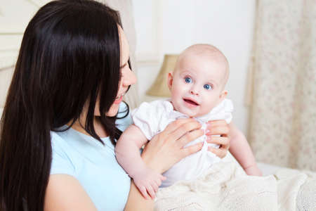 Happy smiling mother with six month old baby girl indoor