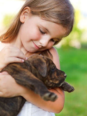Cute little girl hugging her dog puppy. Sunny day. Friendship and care conceptの写真素材