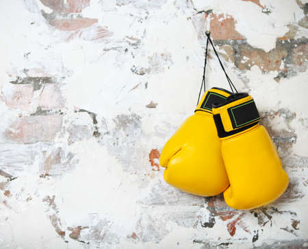 Pair of yellow boxing gloves hanging on a brick wallの写真素材