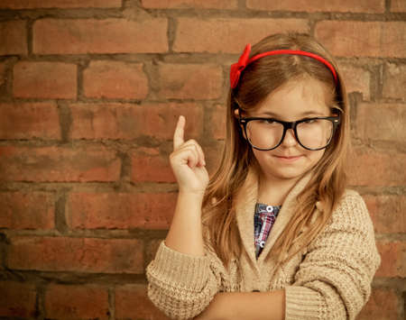 Funny little girl with glasses on brick wall backgroundの写真素材