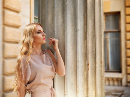 Beautiful blond woman in beige long dress outdoorsの写真素材