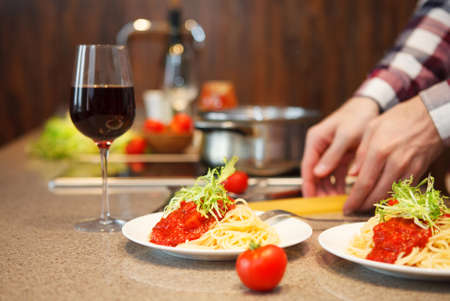 Handsome man cooking at home preparing pasta in a kitchen. Close upの写真素材