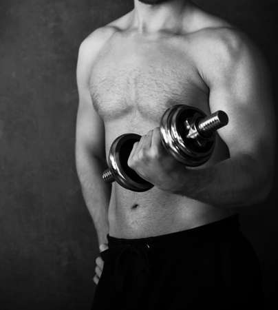 Handsome muscular male model doing exercise for biceps with dumbbellsの写真素材