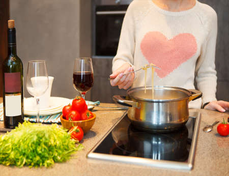 Young woman cooking at home preparing pasta in a kitchenの写真素材