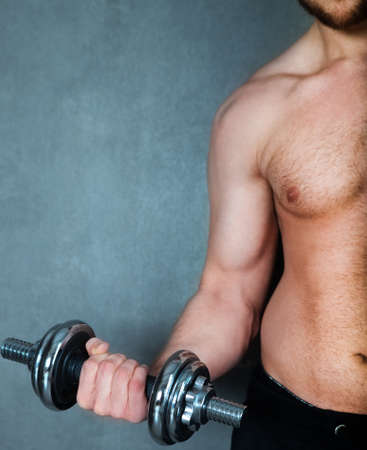 Handsome muscular male model doing exercise for biceps with dumbbellsの写真素材