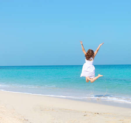 Woman in white dress jumping on the beach. Travel and vacation. Freedom Conceptの写真素材