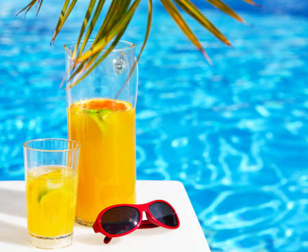 Refreshing orange cocktail lemonade on table near the poolの写真素材