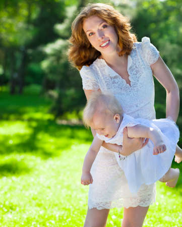 Beautiful Mother And Baby outdoors. Happy mum and her Child playing in Park together. Outdoor Portrait of happy familyの写真素材