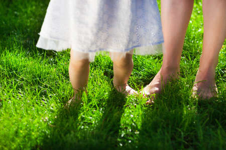 Baby girl taking first steps with mother help in summer gardenの写真素材