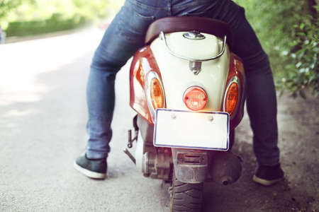 Man riding old retro scooter in a city street. Close upの写真素材