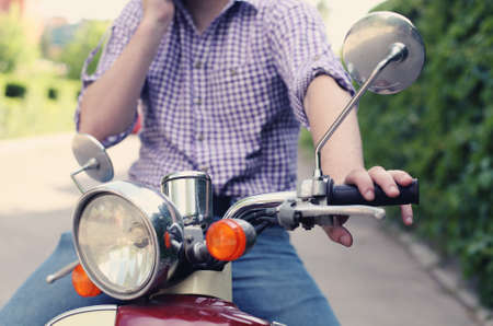 Young man riding old retro scooter in a city street