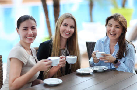 Young women drinking coffee in a cafe outdoors. Shallow depth of fieldの写真素材