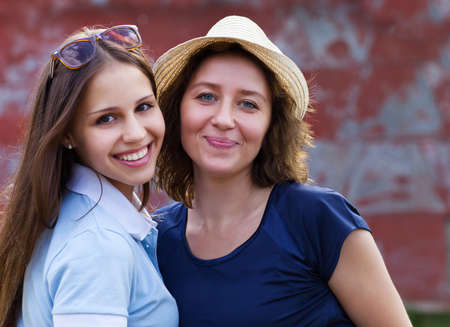 Young smiling woman with her teen daughter outdoorsの写真素材