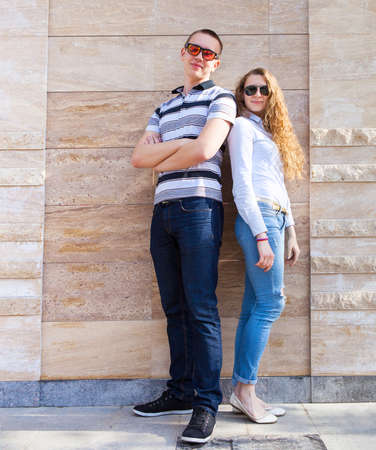 Young couple standing back to back wearing sunglassesの写真素材