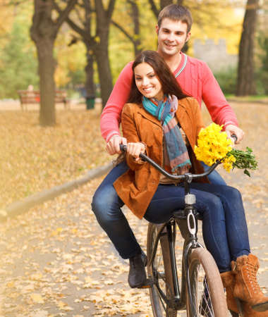 Happy young couple with bicycle walking in autumn parkの写真素材
