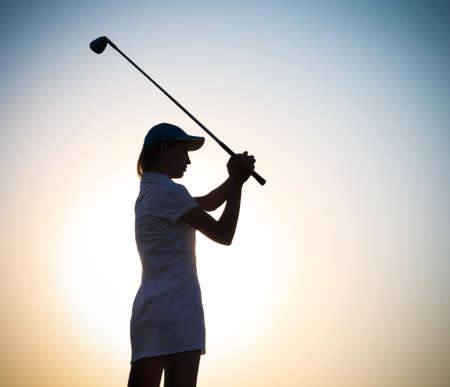 Female golfer playing golf at sunsetの写真素材