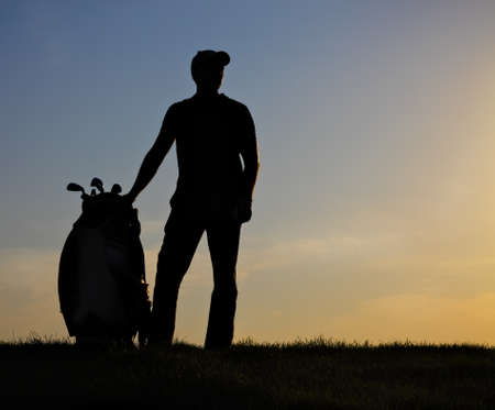 Male golfer playing golf at sunsetの写真素材