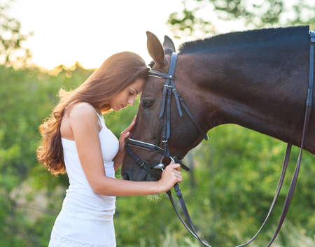 Portrait beautiful woman with long hair next horse. Focus on the horseの写真素材