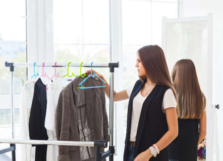 Portrait of attractive teen girl making choices clothes at home