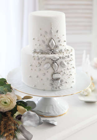 White wedding cake with silver decoration and wedding bouquet with ranunculusの写真素材