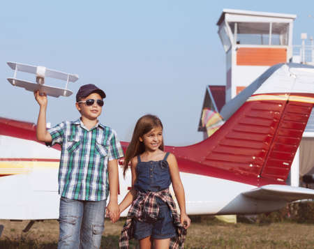 Little boy and little girl pilot with handmade plane at the airportの写真素材