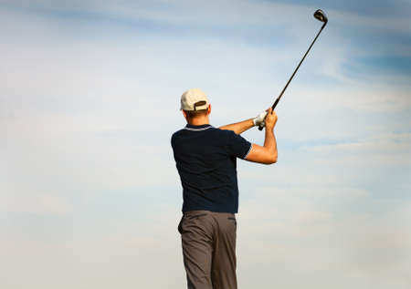 Athletic young man playing golf, golfer hitting fairway shot, swinging clubの写真素材