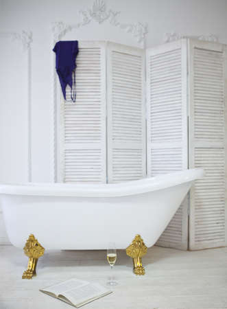 Claw foot bath in a white classical bathroom with champagne and book. Relax conceptの写真素材
