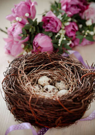 Flowers and easter nest with eggs on rustic wooden background. Spring time. Retro tonedの写真素材