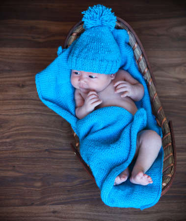 Baby boy laying on blue blanket in the basket on the wooden floorの写真素材