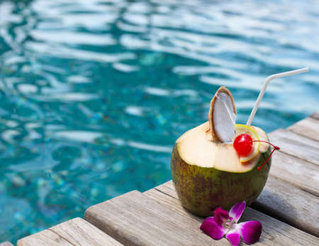 Coconut cocktail with drinking straw by the swimming pool