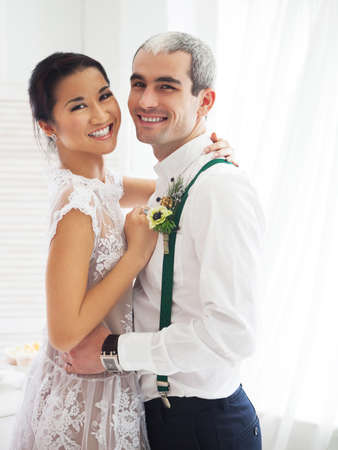 Cheerful married couple standing in white roomの写真素材