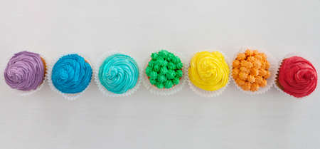 Rainbow Happy Birthday cupcakes on the white background with copy space