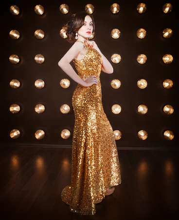 Superstar woman wearing golden shining dress posingの写真素材