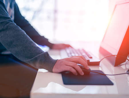 Male hand holding computer mouse with laptop keyboard in the backgroundの写真素材