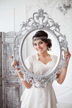 Portrait of the bride with big beautiful eyes on holding silver frame white backgroundの写真素材