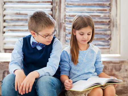 Brother and sister reading book in living roomの写真素材