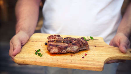 BBQ steak. Barbecue grilled beef steak meat in hands of a man. Healthy food. Barbeque steak dinnerの写真素材