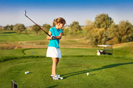 Cute little girl playing golf on a field outdoor. Summertime Cute little girl playing golf on a field outdoor. Summertime